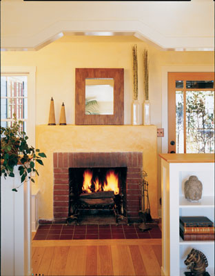 The home’s original fireplace still lends a cozy glow to the living room, while the shapes and finishes around it improve beauty and utility. New built-in bookshelves (topped with salvaged wood) improve spatial definition and provide storage/display space. The walls are gypsum-plastered and casein- glazed, and the original white-oak floors were refinished with a water-based BonKemi sealer.